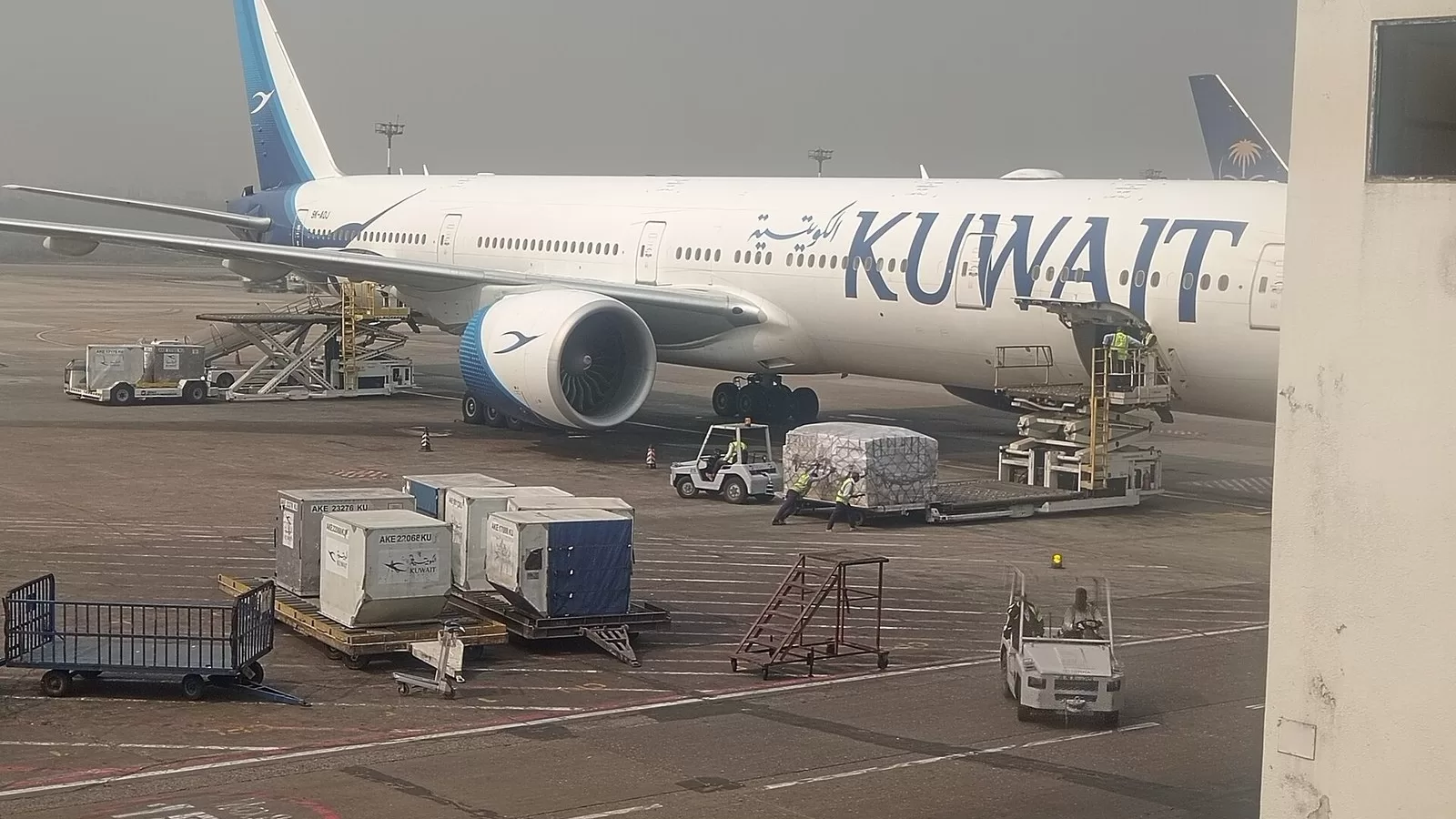 طائرة بوينغ 777 تابعة للخطوط الجوية الكويتية على ساحة المطار وحولها معدات المناولة الأرضية