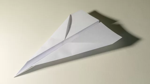 طائرة من ورق ابيض على سطح فاتح