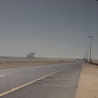 طريق سريع في صحراء الكويت يمتد الى الافق، وسيارات بعيدة على جانبه