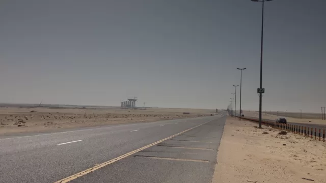 طريق سريع في صحراء الكويت يمتد الى الافق، وسيارات بعيدة على جانبه