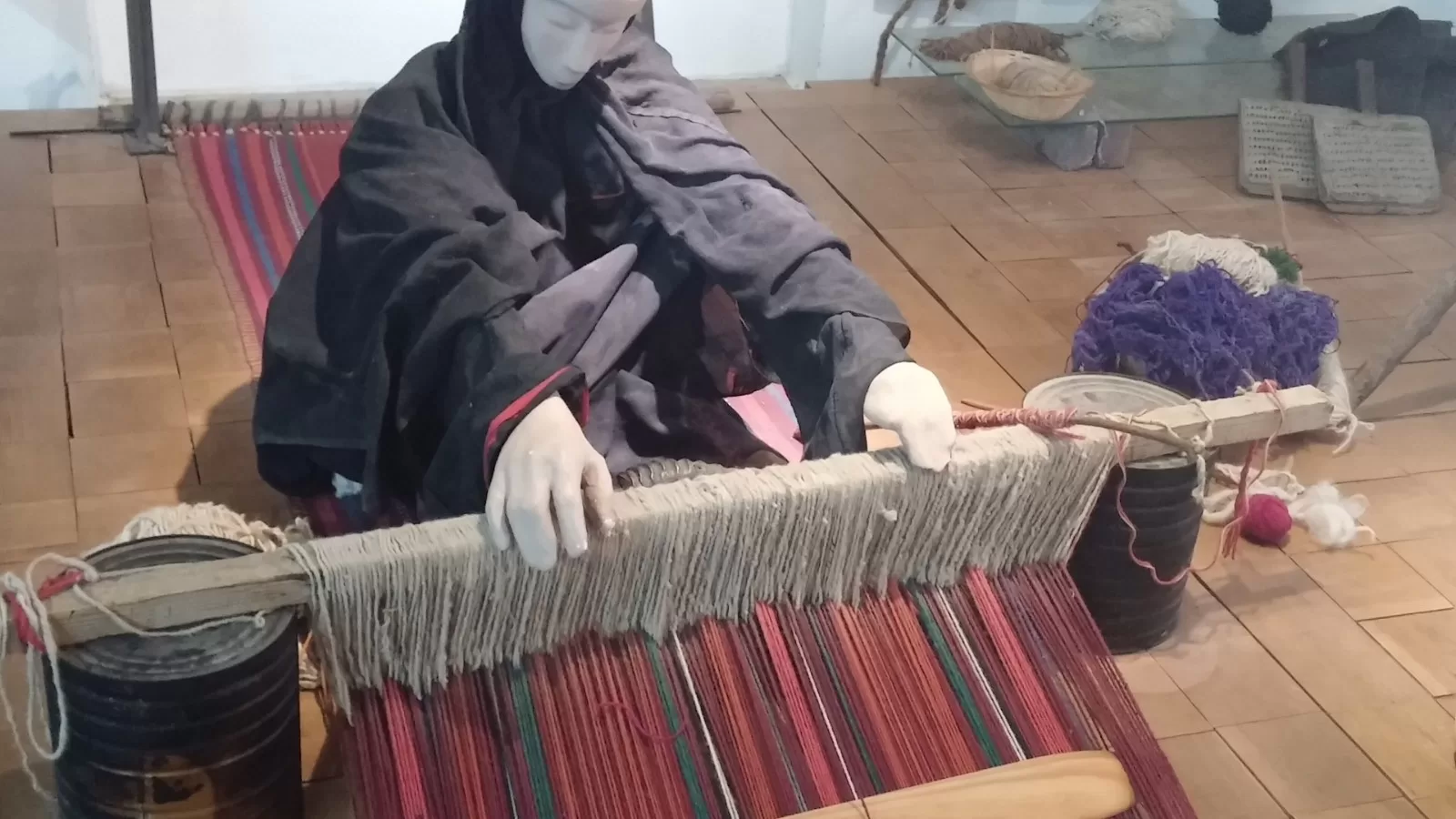 امرأة تنسج على نول ارضي بخيوط ملونة
