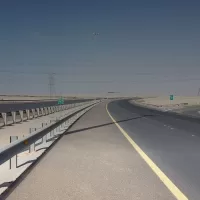 طريق سريع في الكويت بحاجز حديدي على يساره وابراج كهرباء على جانبيه تحت سماء صافية