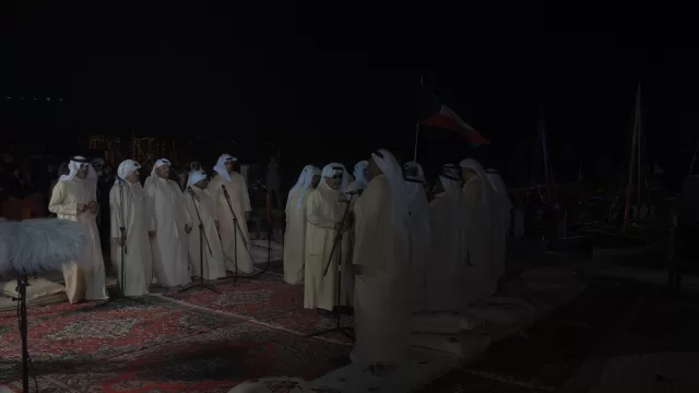 فرقة كويتية تؤدي الغناء الشعبي على سجاد ومساند في الهواء الطلق ليلا