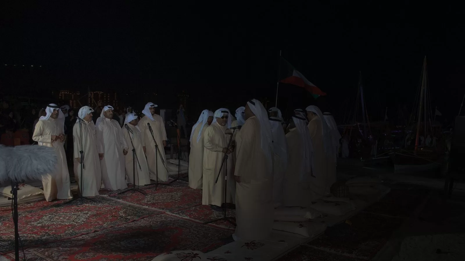 فرقة كويتية تؤدي الغناء الشعبي على سجاد ومساند في الهواء الطلق ليلا