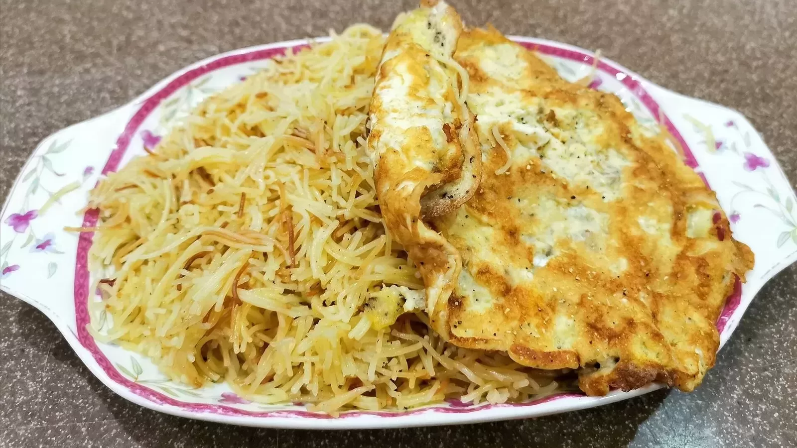 A plate of sweetened vermicelli topped with a thin omelette
