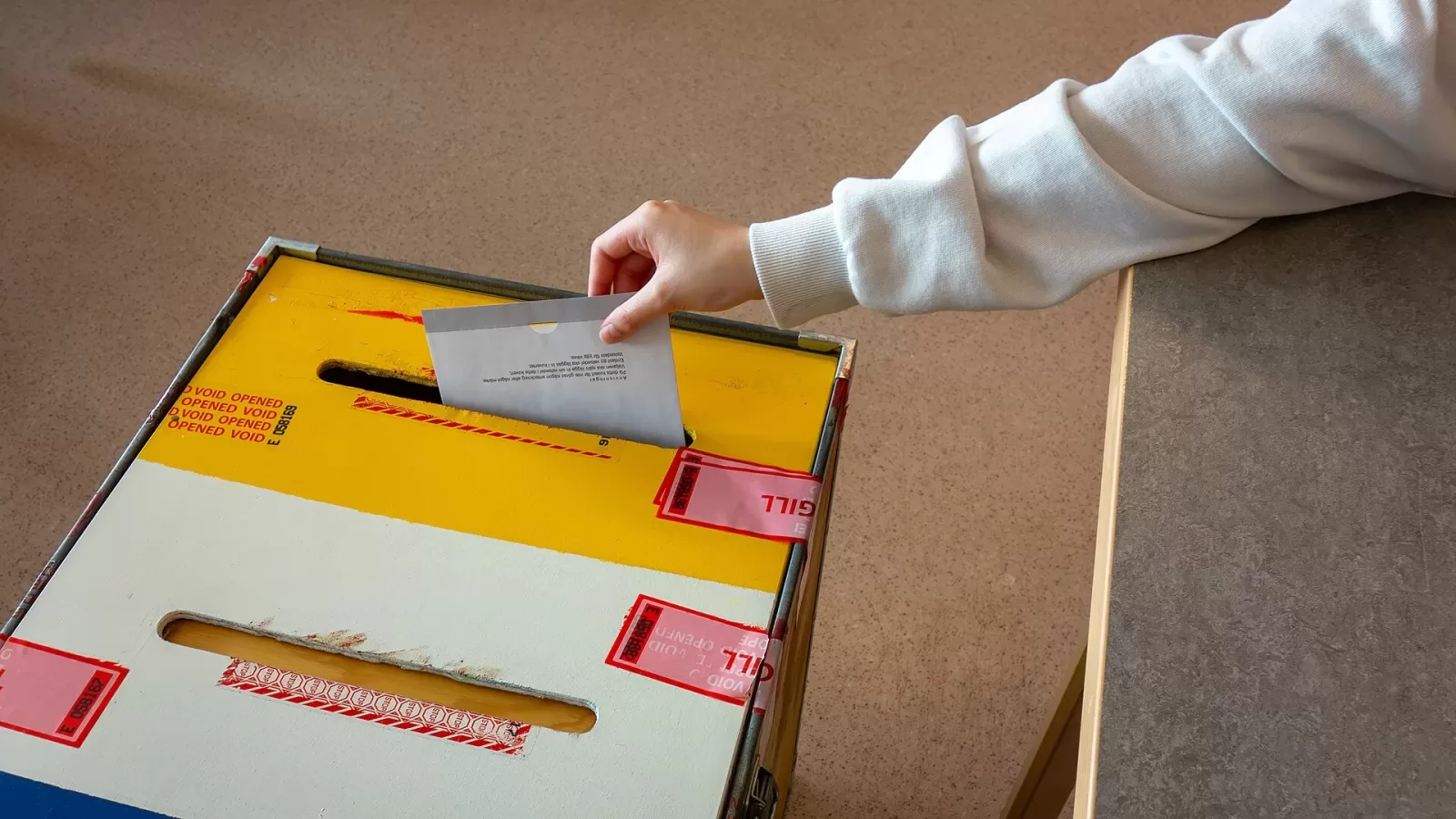A hand placing a ballot paper into a box