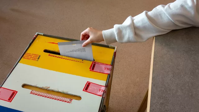 A hand placing a ballot paper into a box