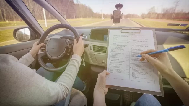 A driving examiner sitting beside a learner driver