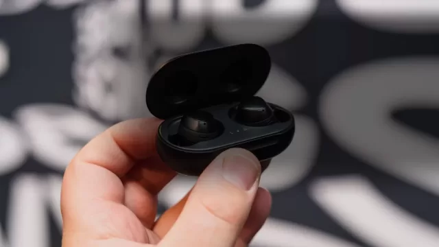 A pair of wireless Galaxy Buds earphones beside their case