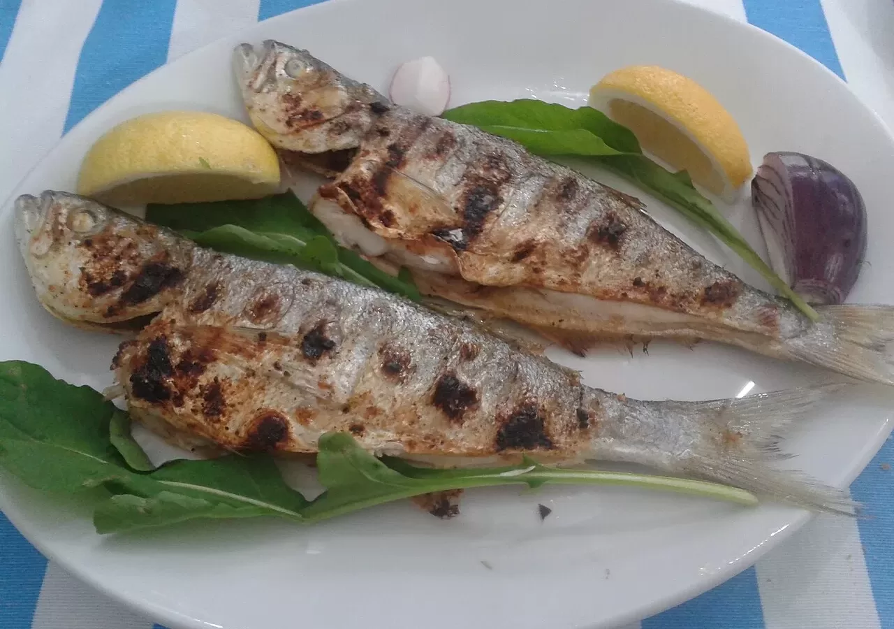 A plate of grilled fish served with lemon on a table