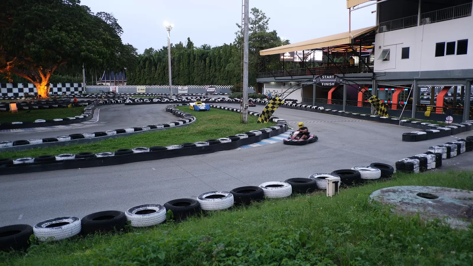 Go-kart speeding around an outdoor circuit at dusk. Source: Wikimedia Commons, File:DSCF0747 A go-kart speeding around a