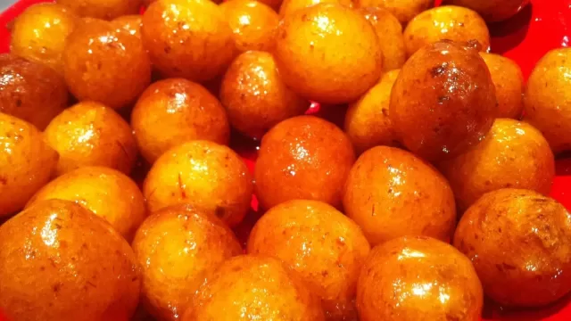 A plate of fried luqaimat dumplings drizzled with syrup