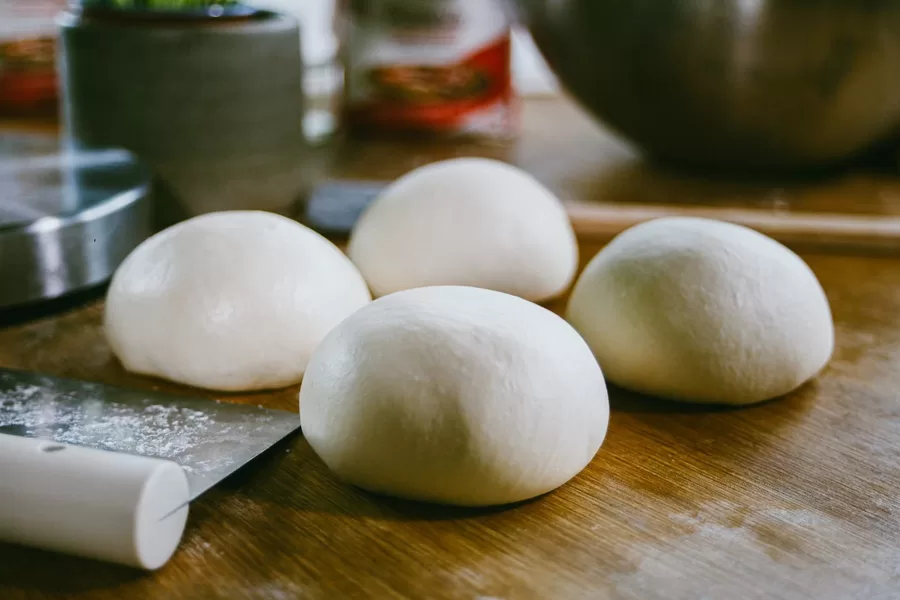 Balls of margoog dough resting on a wooden board