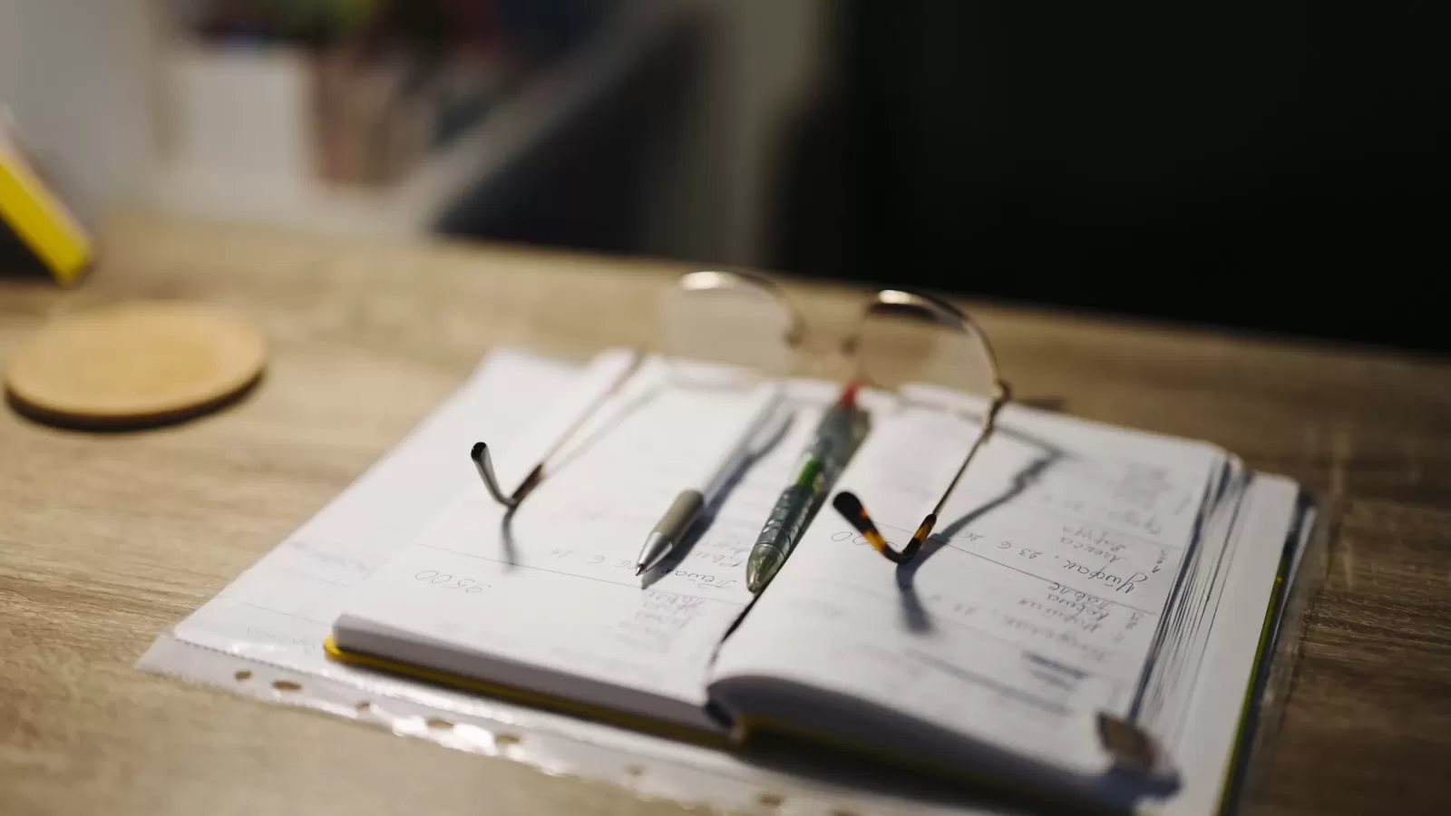 A notebook and a pair of glasses on a desk