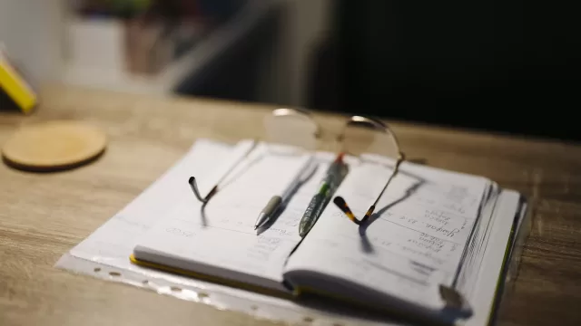 A notebook and a pair of glasses on a desk