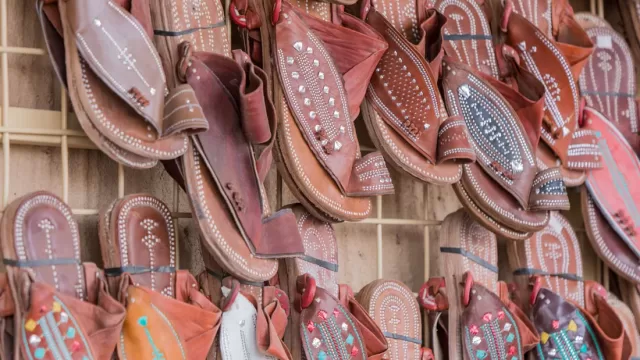 Leather working tools and hand-made sandals on a workbench