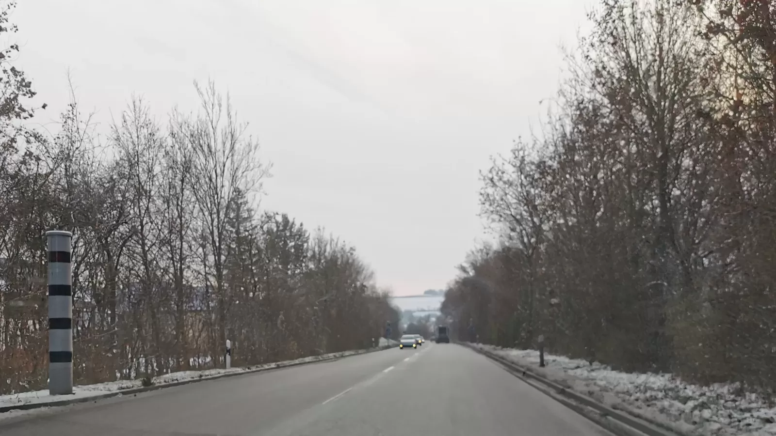 A speed camera on a pole beside a road