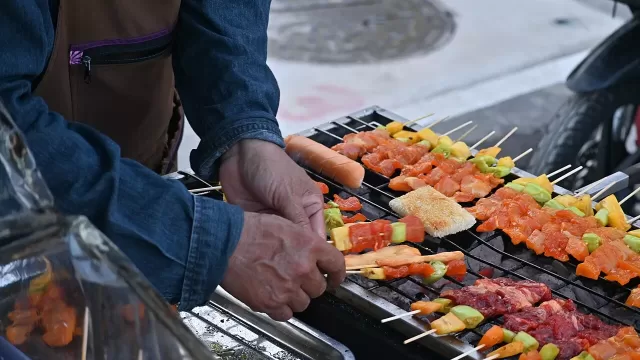 Meat and vegetable skewers cooking on a charcoal grill