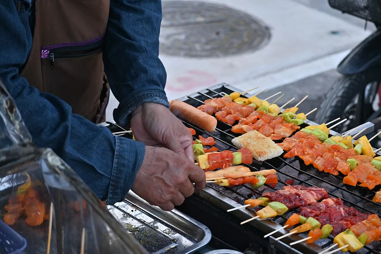 Meat and vegetable skewers cooking on a charcoal grill