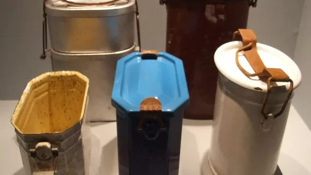 A row of stacked metal tiffin carriers with handles