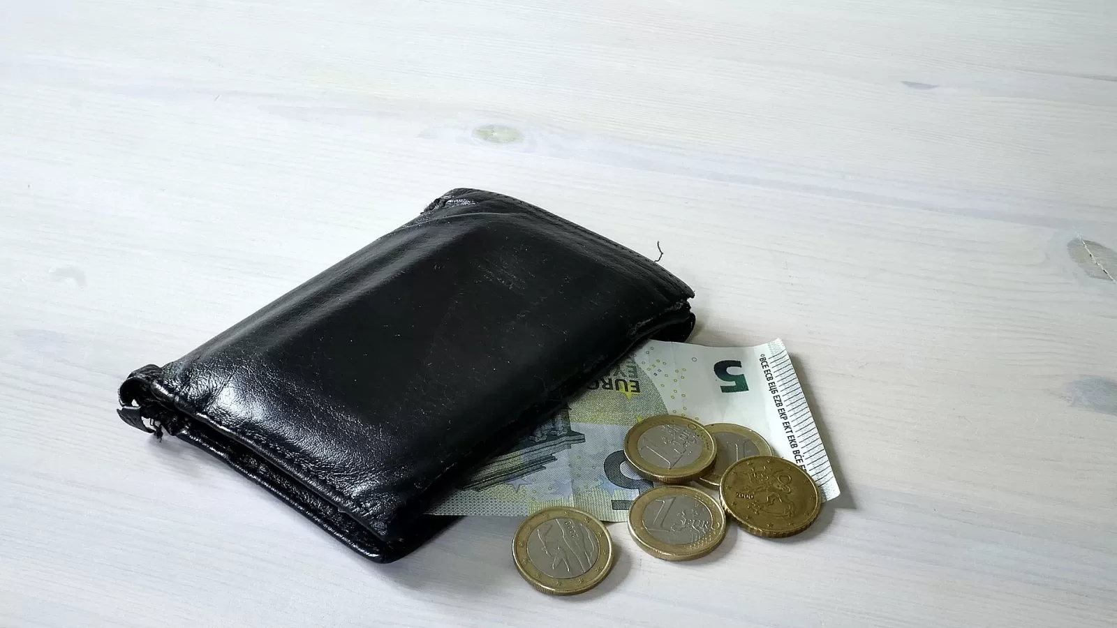 A wallet with coins beside it