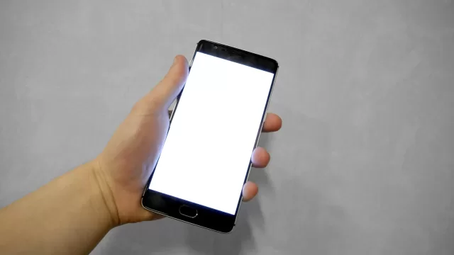 A hand holding a phone with a blank screen