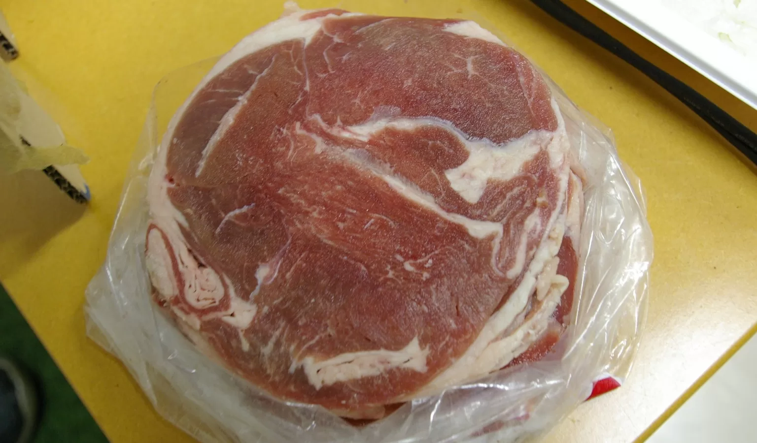 Sliced lamb thawing in a plastic bag on a kitchen counter