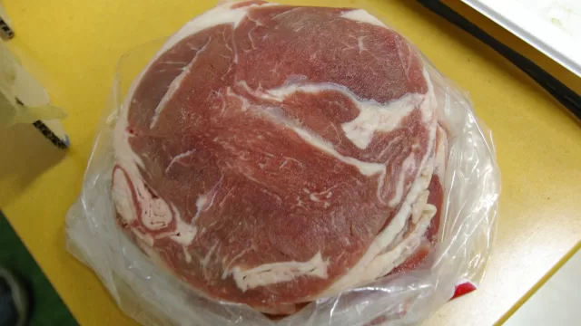 Sliced lamb thawing in a plastic bag on a kitchen counter